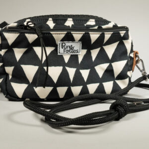 Sac zippé Watermill × Pures Folies en toile imperméable motif triangles noir et blanc, zip XXL noir mat, départs d'anneaux en cuir camel, sangle paracord noir détachable avec mousquetons, étiquette Pures Folies en façade