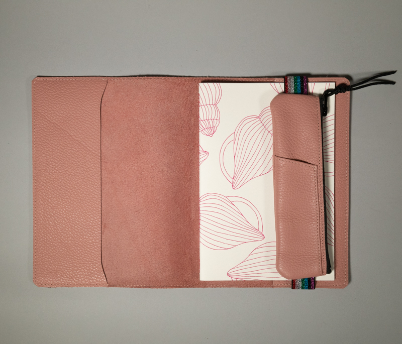 couverture de carnet en cuir grainé rose poudré, présenté ouvert avec carnet papier blanc et rose et trousse élastique rose poudré coordonnée