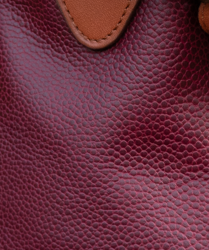détails du grain façon galuchat du cuir bordeau, contrasté par un cuir lisse camel