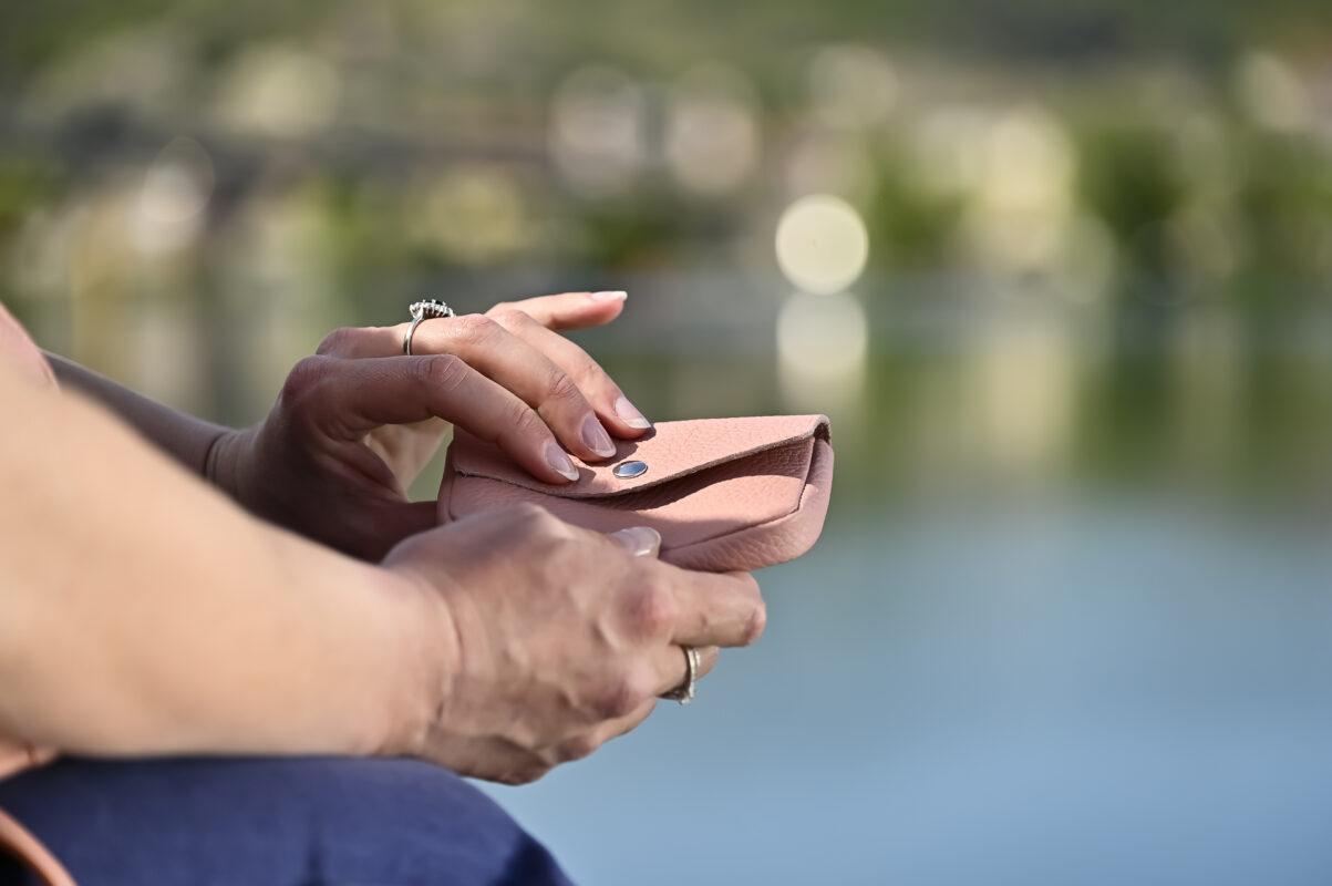 porte monnaie clutch en cuir grainé rose poudré dans les mains d'un mannequin au bord de l'eau collection intemporels
