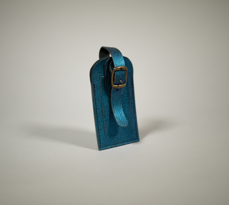 Porte étiquette de bagage en cuir grainé bleu lagon avec fermeture par pression et boucle en laiton vieilli.
