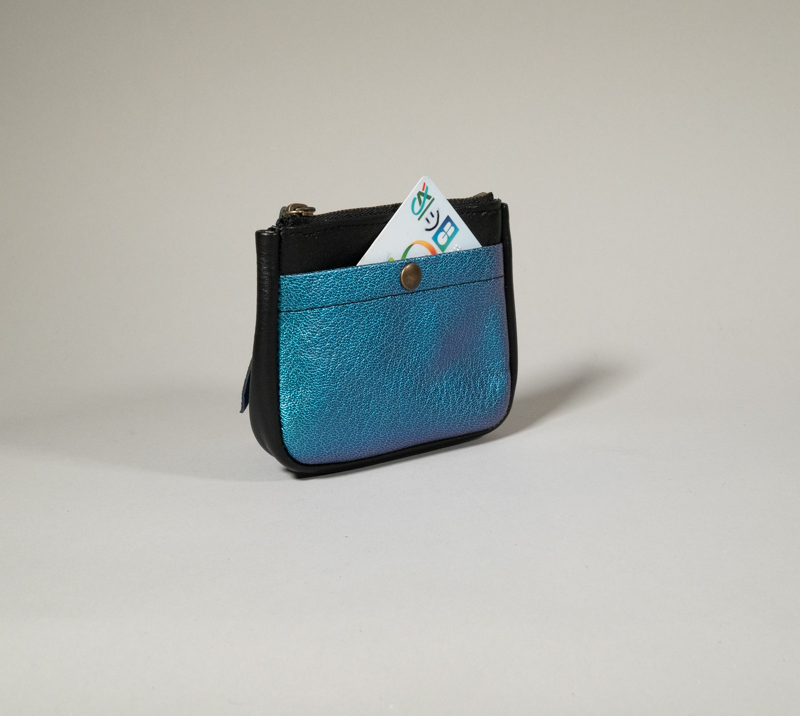 porte monnaie en cuir noir , zippé et compartiment cartes à l'avant contrasté bleu lagon, fermé par pression métallique, volume donné par un soufflet