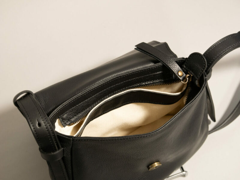 détails de l'intérieur en tissu et cuir, de la besace mini INTEMPORELS, en cuir noir grainé et cuir contrasté noir lisse