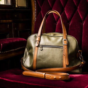 sac bowling bronze et camel posé sur siège matelassé de wagon en velours rouge