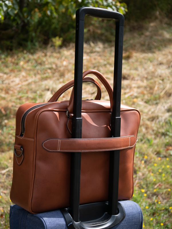 sac en cuir 24h james maintenu sur une valise avec l'option sangle arrière pour trolley