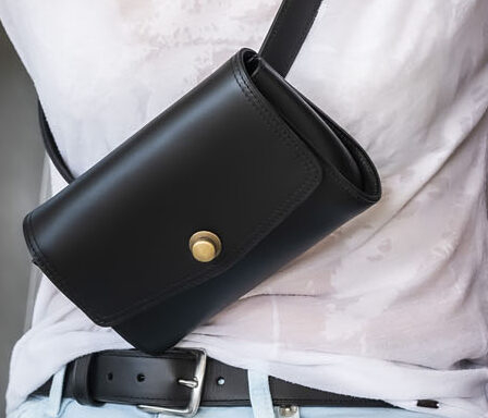 sac banane pochette de ceinture en cuir noir lisse, fermé par un rabat et un fermoir en laiton